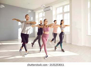 Group of beautiful young people doing fitness exercises at the gym. Happy, cheerful, smiling friends, motivated to stay in good shape, enjoying sports dance workout class with a professional coach - Powered by Shutterstock