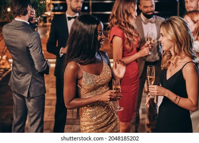 Group of beautiful young people in formalwear communicating and smiling while spending time on luxury party - Shutterstock ID 2048185202