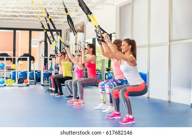 Group Of Beautiful Young Women Working Out On TRX And Smiling.