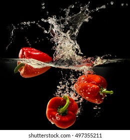 Group of bell pepper falling in water with splash on black background.