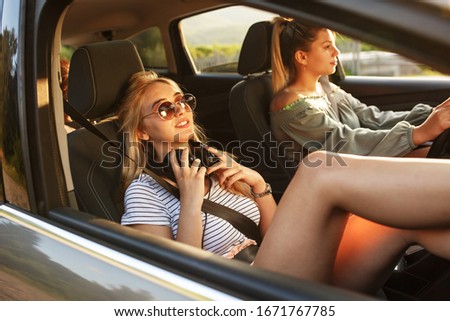 Similar – Two young women resting sitting inside of car