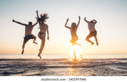 Group of best friends having fun jumping at the beach at sunset on vacation. Young happy people enjoy the holiday - Shutterstock ID 1401997040