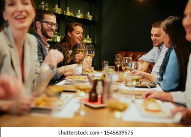 Group Of Best Friends Sitting In Restaurant, Having Dinner, Drinking Wine And Having Fun.