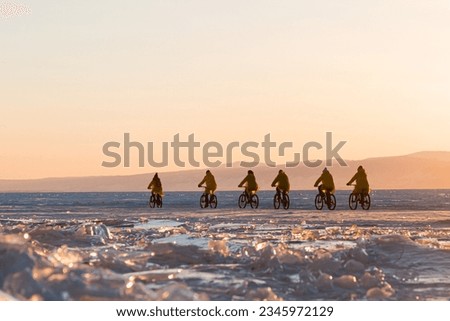 a group of bicyclists riding at sunset on frozen Lake Baikal