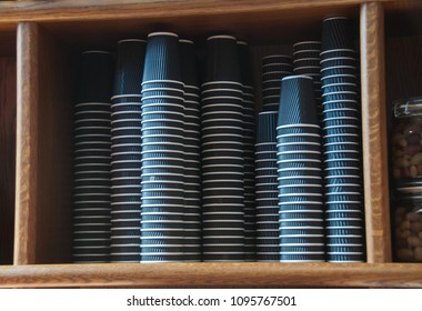 Group Of Black Disposable Paper Coffee Cups Stacking In A Wooden Shelf