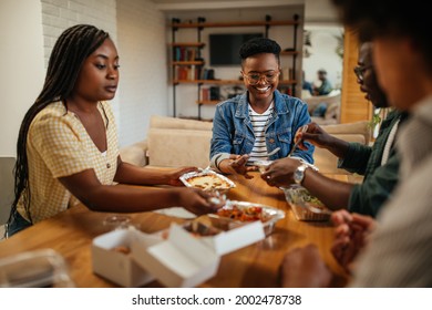 Group Of Black Friends Eating Takeout Food At Home. They Are Chatting And Having A Relaxing Lunch Time Together