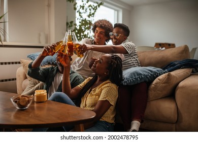 Group of black friends sitting on the floor in the living room, having fun while toasting with alcohol - Powered by Shutterstock