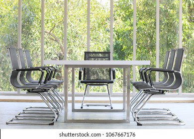 Group Of Black  Meeting Chairs In White Conference Room Taken With Natural Green Tree In Background.