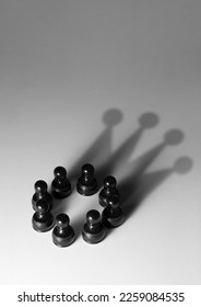 Group of black pawns with shadow shaped as a crown