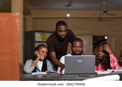a group of black students studying together, using a laptop to discuss their work