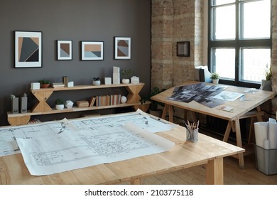 Group of blueprints with architectural sketches on large wooden table in contemporary office or workshop - Shutterstock ID 2103775118