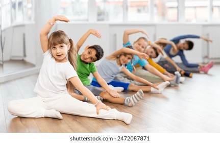 Group of boys and girls with teacher doing warm-up exercises before dancing in studio - Powered by Shutterstock