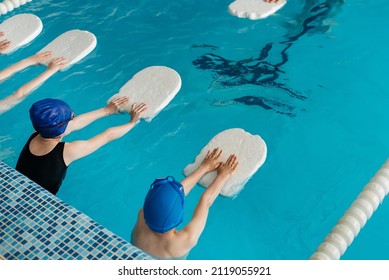 A group of boys and girls train and learn to swim in a modern swimming pool with an instructor. Development of children's sports. Healthy parenting and promotion of children's sports. - Shutterstock ID 2119055921