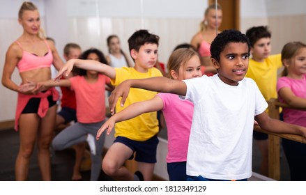 Group of boys and girls training along ballet bar at dance class