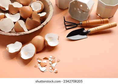 Group of broken egg shells ,plastic flower pot and set of gardening on beige colored background. Recycling kitchen waste, Crushed egg shells for the compost and garden.