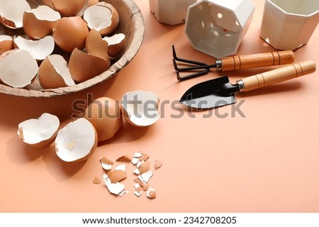 Group of broken egg shells ,plastic flower pot and set of gardening on beige colored background. Recycling kitchen waste, Crushed egg shells for the compost and garden.