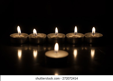 Group of burning candles on  black background.