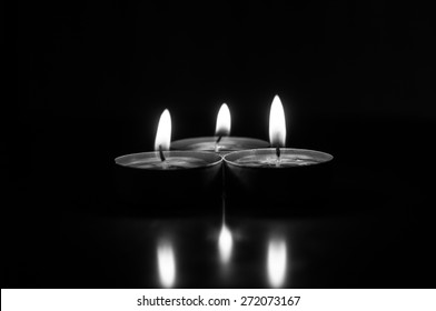Group of burning candles on  black background. Black and white