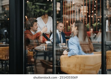 Group of business colleagues engaged in a discussion in a modern cafe, seen through a glass window. Collaborative meeting, professional interaction, and teamwork concept. - Powered by Shutterstock