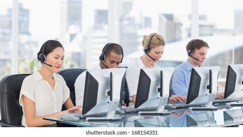 Group of business colleagues with headsets using computers at office desk - Powered by Shutterstock