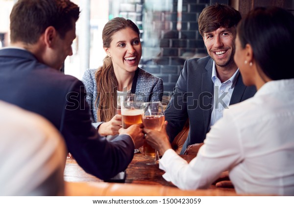 Group Of Business Colleagues\
Making A Toast As They Meet For Drinks And Socialize In Bar After\
Work