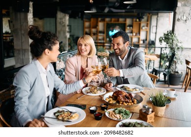 Group of business colleagues toasting with wine while having lunch together in a restaurant.  - Powered by Shutterstock