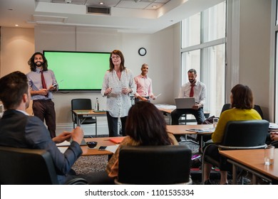 Group Of Business Men And Women Giving A Presentation To Another Small Group Of Business Men And Women.