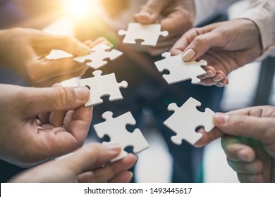 A group of business people assembling jigsaw puzzle. The concept of cooperation, teamwork, help and support in business. - Shutterstock ID 1493445617