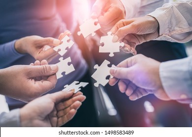 A group of business people assembling jigsaw puzzle. The concept of cooperation, teamwork, help and support in business.