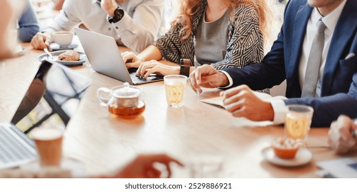 Group of business people in casual meeting, using laptops and taking notes. Business attire, diverse team, collaborative workspace, discussion and teamwork. Business people working together at cafe - Powered by Shutterstock