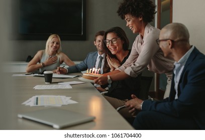 Group of business people celebrating a female executive's birthday in conference room. Team celebrating colleague's birthday in office during a meeting. - Powered by Shutterstock