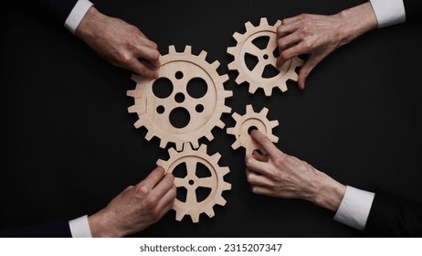 Group of business people connecting wooden cogwheels together on black background - Shutterstock ID 2315207347