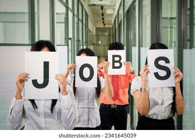 Group of business people covering their face with JOBS writing on papers