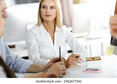 Group of business people discussing questions at meeting. Portrait of blond businesswoman in sunny office