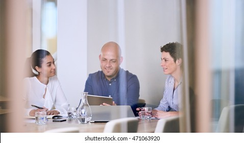 Group Of Business People In Discussions In Modern Office Building Conference Room Shot From Outside The Room Through The Glass Walls.