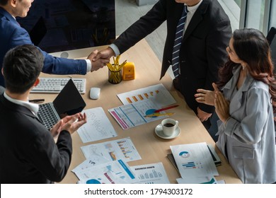 Group business people handshake at meeting table in office together with confident shot from top view . Young businessman and businesswoman workers express agreement of investment deal.