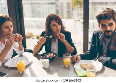Group of business people having breakfast in company's restaurant. Focus on the woman in the middle