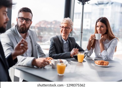 Group of business people having breakfast in company's restaurant. Focus on the women