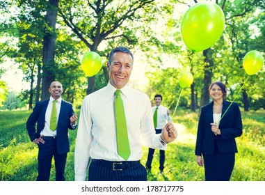 Group Of Business People Holding Green Balloons In Forest 