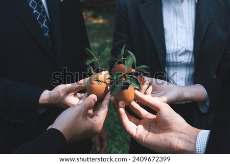 Group of business people holding repuposed eggshell transformed into fertilizer pot, symbolizing commitment to nurture and grow sprout or baby plant as part of a corporate reforestation project. Gyre