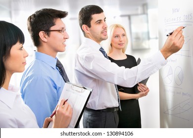 Group Of Business People Looking At The Graph On Flipchart