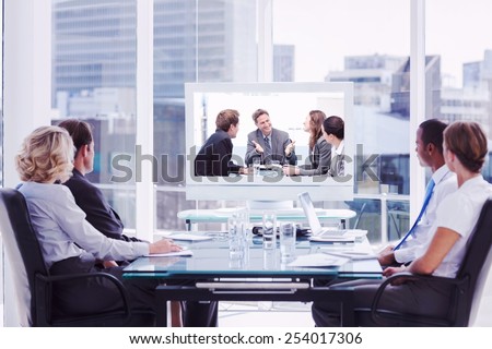Group of business people looking at a screen against happy team laughing together at a meeting