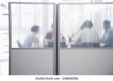 Group Of Business People In Meeting Behind Translucent Wall In Office