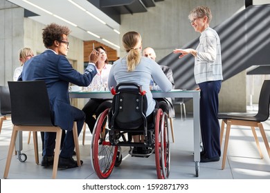 Gruppe von Geschäftsleuten in einem Treffen mit einem Kollegen in einem Rollstuhl zur Inklusion