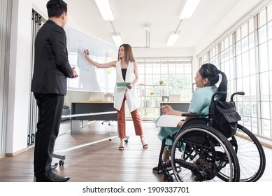 Group Of Business People In A Meeting With Colleague, Businessman, Businesswoman And Disabled Working Woman On Wheelchair, Working Together In Office Workplace