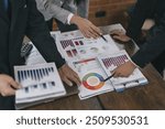 Group of business people meeting, discussion, brainstorming, pointing at graphs and charts to analyze market data, calculating balance sheets, accounts, net profits to plan company sales strategies.