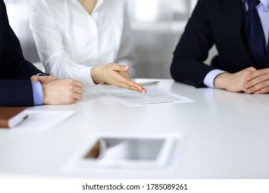 Group of business people, men and a woman, discuss details of a contract at meeting in a modern office. Discussion at negotiation or workplace. Teamwork, partnership and business concept - Shutterstock ID 1785089261