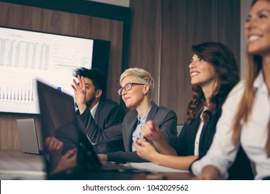 Group Of Business People On A Meeting In A Conference Room. Woman Raises Hand To Ask A Question