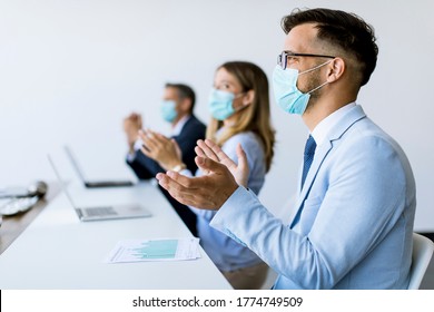 Group Of Business People With Protection Masks Clapping Hands After Successful Business Meeting In The Modern Office