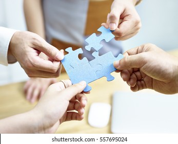 group of business people putting jigsaw pieces together